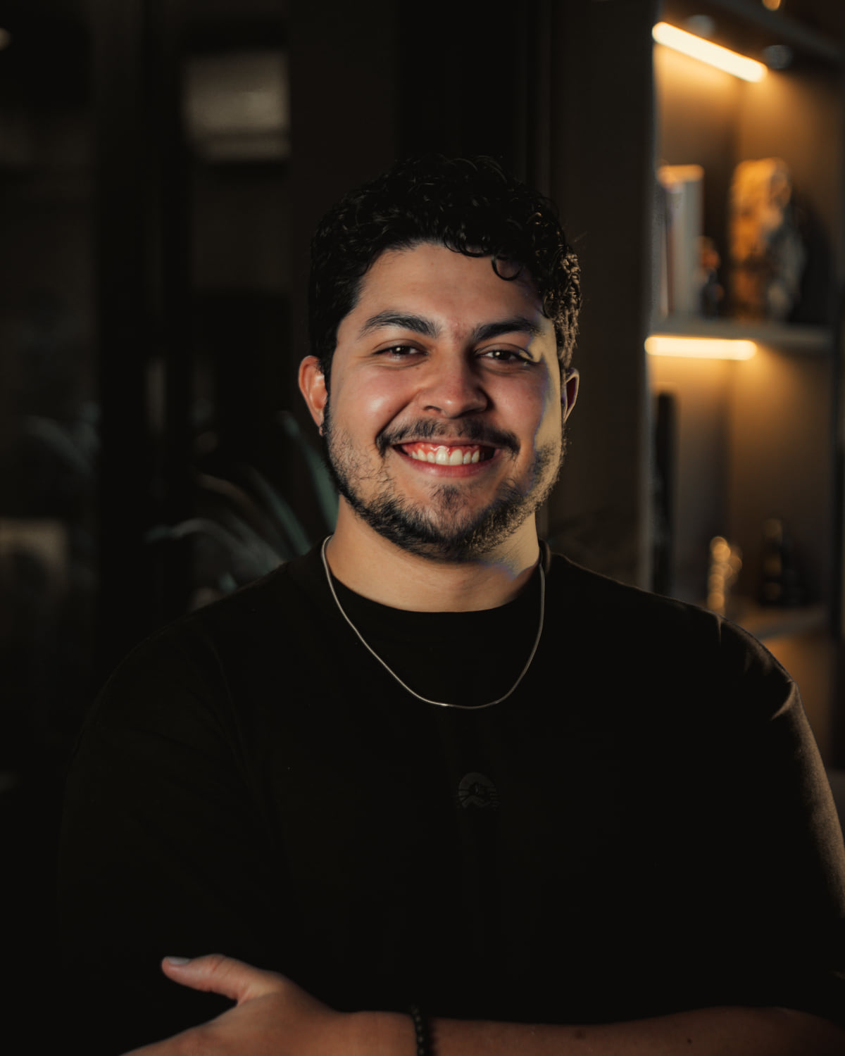Mateus Nobre, de camiseta preta, sorrindo de braços cruzados